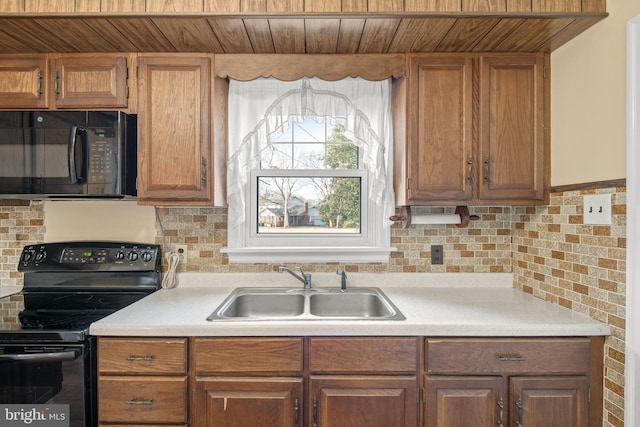 kitchen featuring wooden ceiling, a sink, light countertops, backsplash, and black appliances