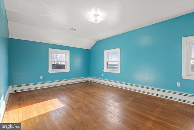 spare room with a baseboard radiator, visible vents, wood-type flooring, and a wealth of natural light