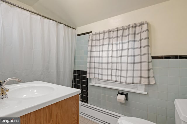 full bathroom featuring a baseboard radiator, toilet, vanity, tile walls, and vaulted ceiling