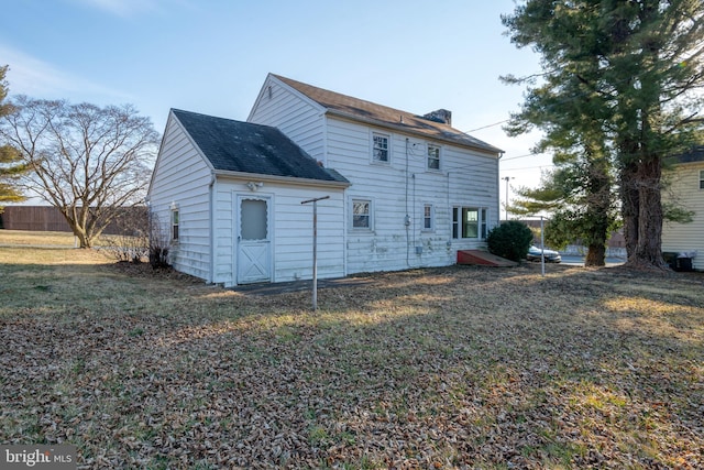 rear view of property featuring fence and a yard