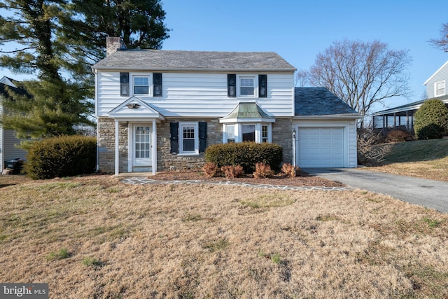 view of front of house featuring an attached garage, stone siding, a chimney, and aphalt driveway