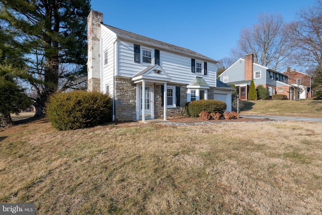 traditional home with stone siding, a front lawn, a chimney, and an attached garage