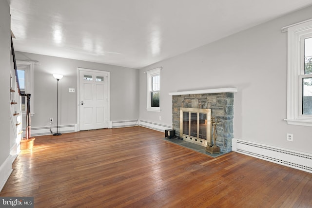 unfurnished living room featuring baseboard heating and wood-type flooring