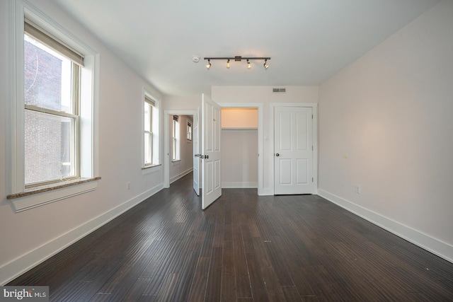 unfurnished bedroom featuring baseboards, visible vents, and dark wood-style flooring