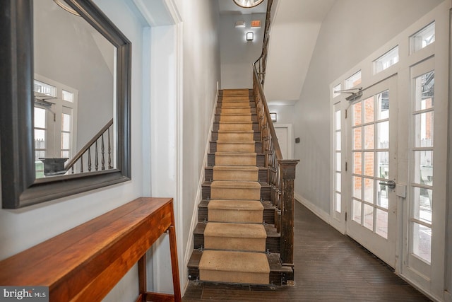 stairway with lofted ceiling, baseboards, wood finished floors, and french doors