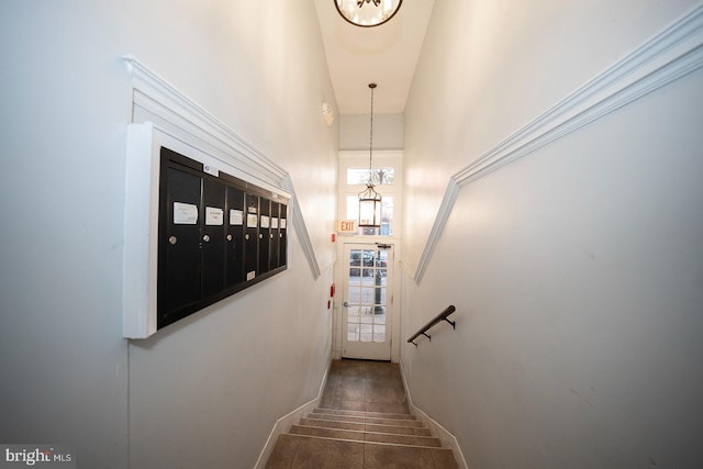 stairway featuring a high ceiling, tile patterned flooring, mail area, and baseboards