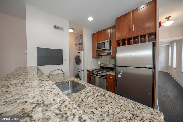 kitchen with tasteful backsplash, visible vents, stacked washer and clothes dryer, stainless steel appliances, and a sink