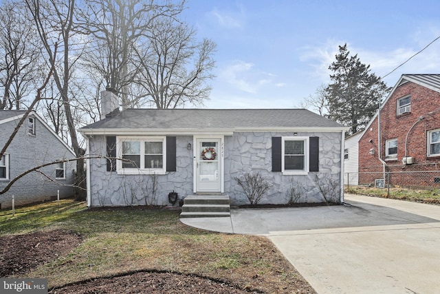 bungalow-style house with roof with shingles, a chimney, entry steps, fence, and stone siding