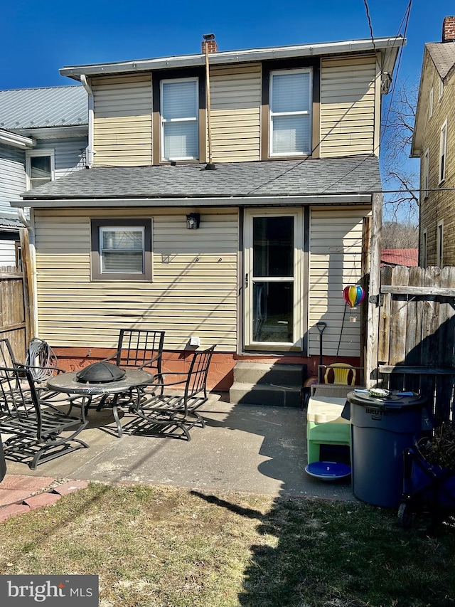 rear view of house featuring entry steps, a patio, a fire pit, and fence