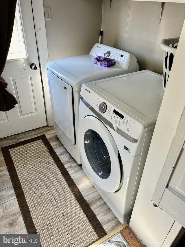 washroom with laundry area, washing machine and dryer, and light wood-style flooring