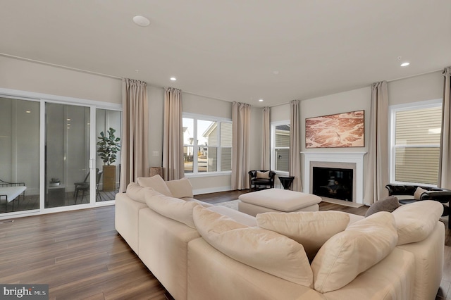 living room with recessed lighting, a fireplace with flush hearth, and wood finished floors