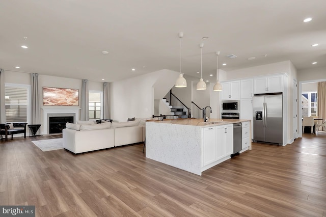 kitchen featuring a sink, a glass covered fireplace, open floor plan, stainless steel fridge with ice dispenser, and built in microwave