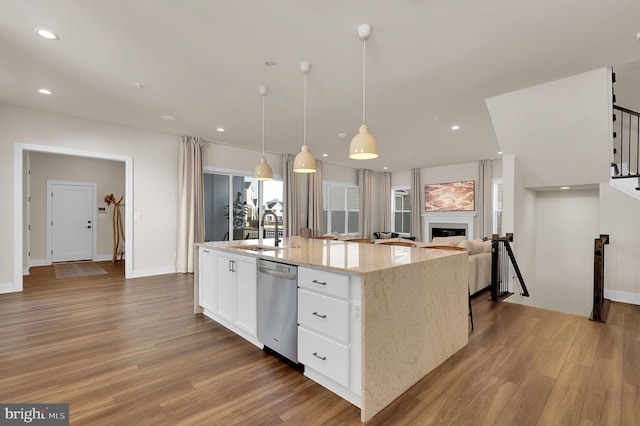 kitchen with a sink, stainless steel dishwasher, wood finished floors, white cabinetry, and recessed lighting