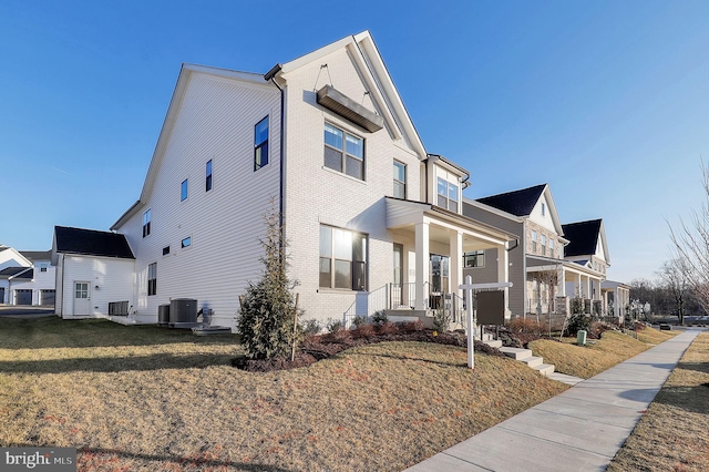 view of property exterior featuring cooling unit, a residential view, brick siding, and a yard