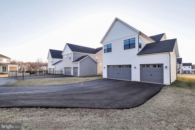 exterior space with aphalt driveway, a garage, fence, and a residential view