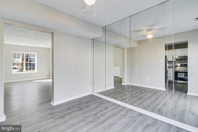 interior space featuring ceiling fan, wood finished floors, visible vents, and baseboards