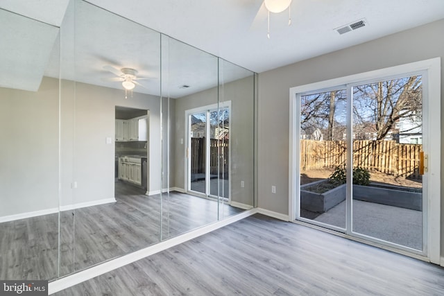 interior space with a healthy amount of sunlight, visible vents, a ceiling fan, and wood finished floors