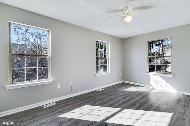 unfurnished room featuring baseboards, visible vents, ceiling fan, and wood finished floors