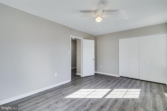 unfurnished bedroom with a ceiling fan, a closet, baseboards, and wood finished floors