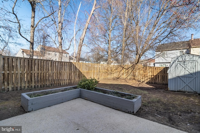 view of patio featuring a storage shed, a fenced backyard, and an outbuilding