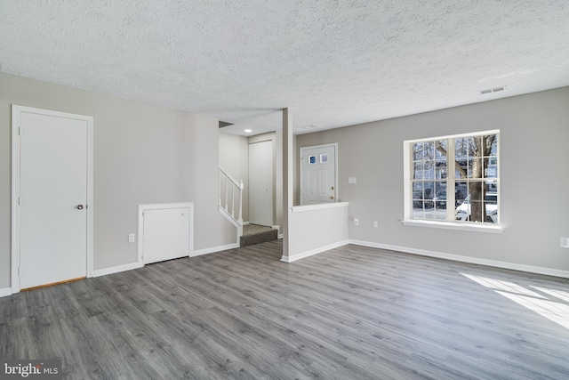 interior space with baseboards, a textured ceiling, stairway, and wood finished floors