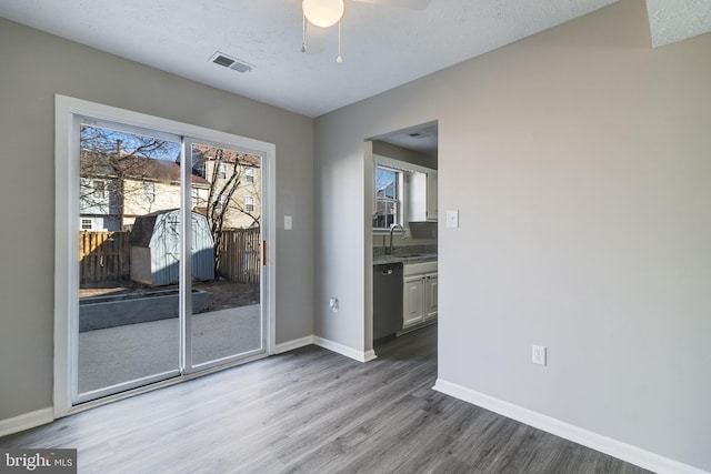 entryway featuring visible vents, a sink, a textured ceiling, wood finished floors, and baseboards