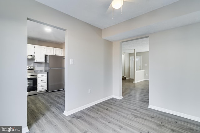 kitchen with stainless steel appliances, light wood finished floors, white cabinetry, and baseboards