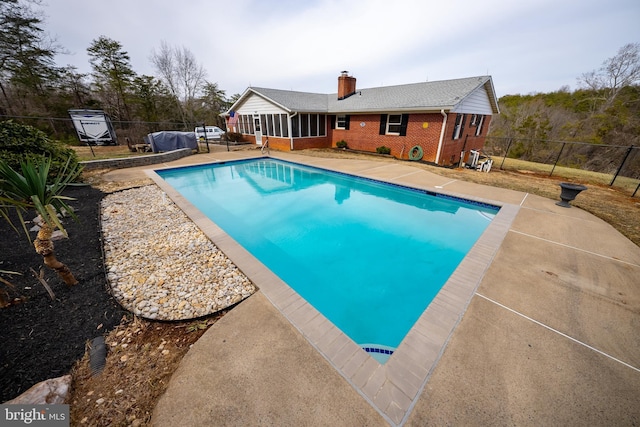 view of swimming pool featuring a sunroom, a fenced backyard, a patio area, and a fenced in pool