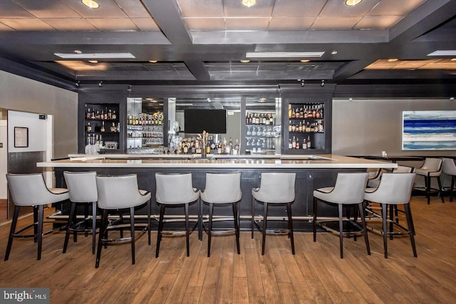 bar with a community bar, beam ceiling, coffered ceiling, and wood finished floors