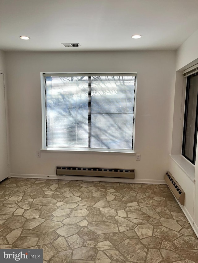 empty room with a baseboard radiator, recessed lighting, visible vents, baseboard heating, and stone finish floor