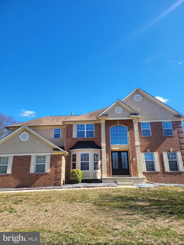 view of front of property with a front yard, french doors, and brick siding