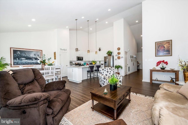 living area with high vaulted ceiling, dark wood-type flooring, and recessed lighting