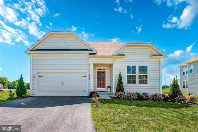 view of front facade with a shingled roof, an attached garage, driveway, and a front lawn