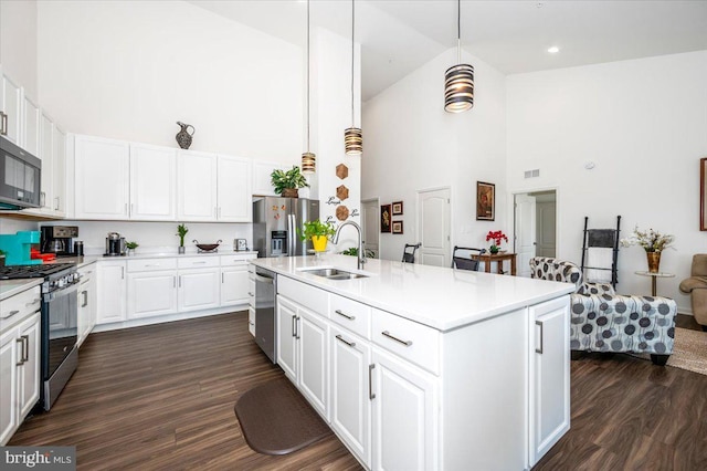 kitchen with stainless steel appliances, dark wood-style flooring, a sink, white cabinets, and light countertops