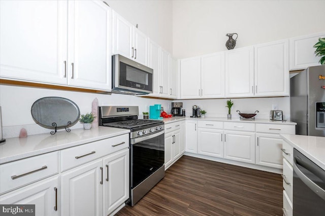 kitchen with light countertops, appliances with stainless steel finishes, dark wood-type flooring, and white cabinets