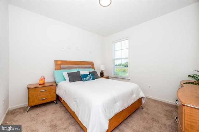 bedroom featuring light carpet and baseboards