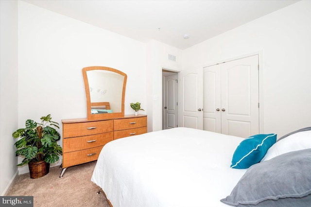 bedroom featuring a closet, light colored carpet, visible vents, and baseboards