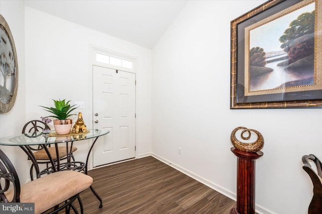 foyer with dark wood-style floors, baseboards, and vaulted ceiling