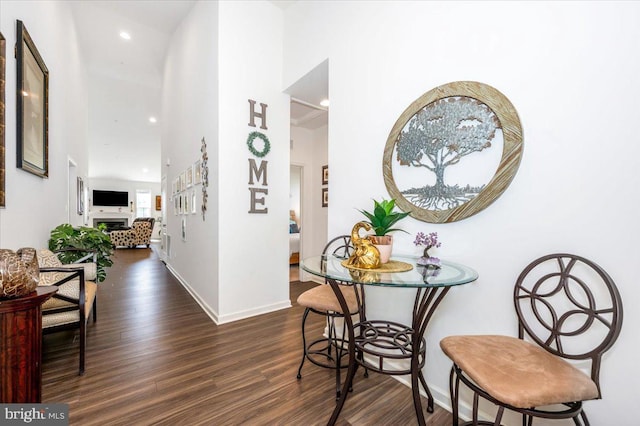 hall with recessed lighting, dark wood finished floors, a towering ceiling, and baseboards