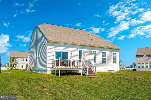 rear view of property featuring roof with shingles, a yard, and a wooden deck