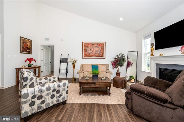 living room with baseboards, visible vents, wood finished floors, and a glass covered fireplace