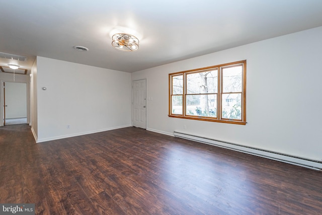 unfurnished room with visible vents, baseboards, baseboard heating, dark wood-style floors, and attic access