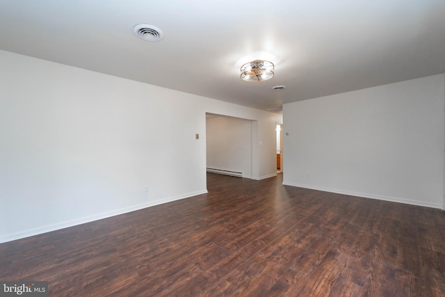 spare room featuring baseboard heating, dark wood finished floors, visible vents, and baseboards