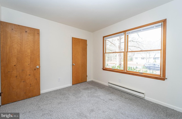 carpeted spare room with a baseboard heating unit and baseboards