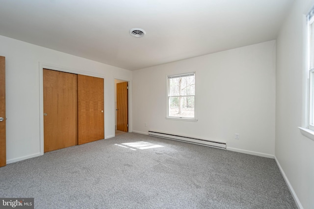 unfurnished bedroom featuring visible vents, baseboards, baseboard heating, a closet, and carpet