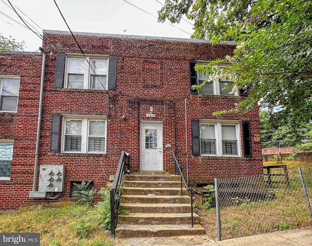 townhome / multi-family property featuring entry steps, brick siding, and fence