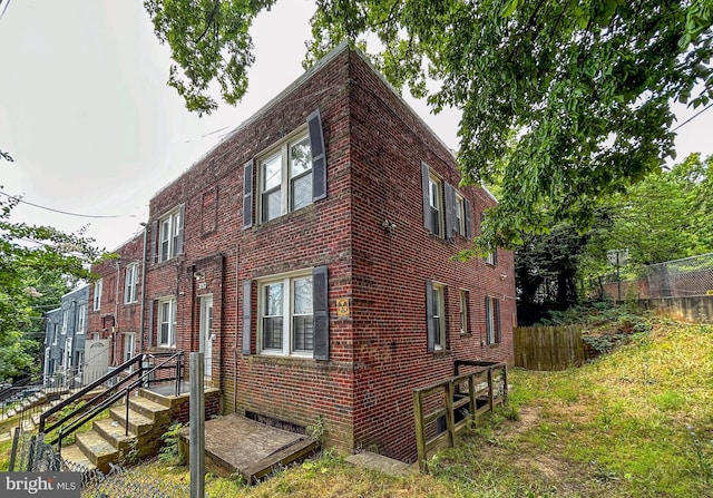 view of side of home featuring brick siding and fence