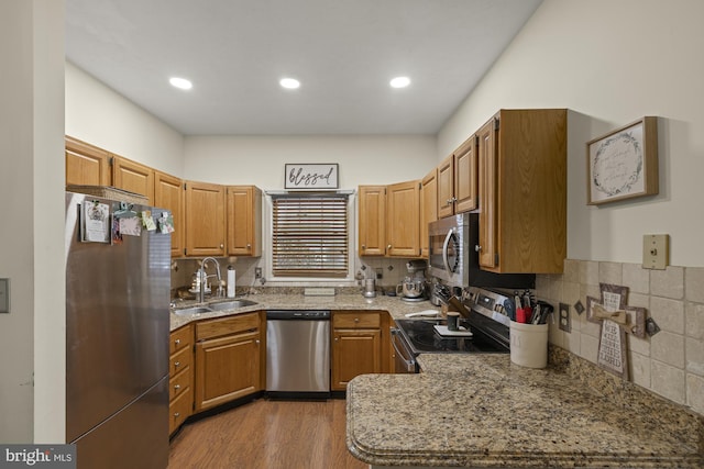 kitchen with stainless steel appliances, wood finished floors, backsplash, and a sink