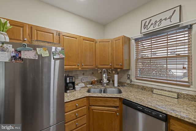 kitchen featuring light stone countertops, appliances with stainless steel finishes, decorative backsplash, and a sink