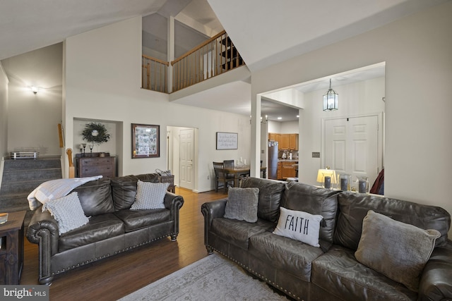 living room with stairs, high vaulted ceiling, and wood finished floors